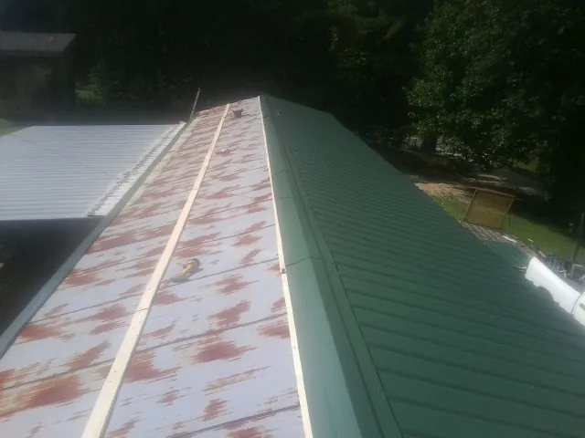 Old rusted panels beside newly installed green metal roofing — Wind Damage Roof Repair by Roofing Brothers in Fountainville