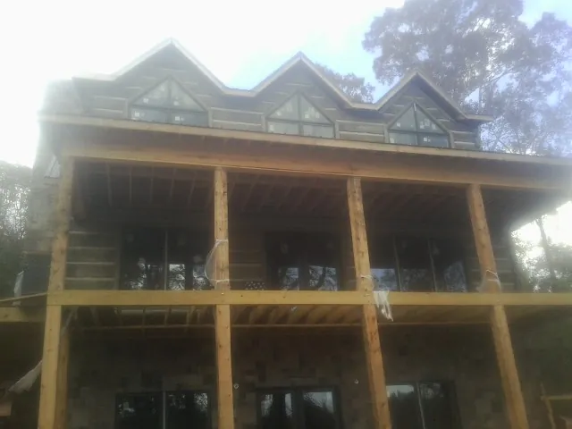 Dormers and porch framing on a large log home under construction — Roof Coating work by our crew in Fountainville