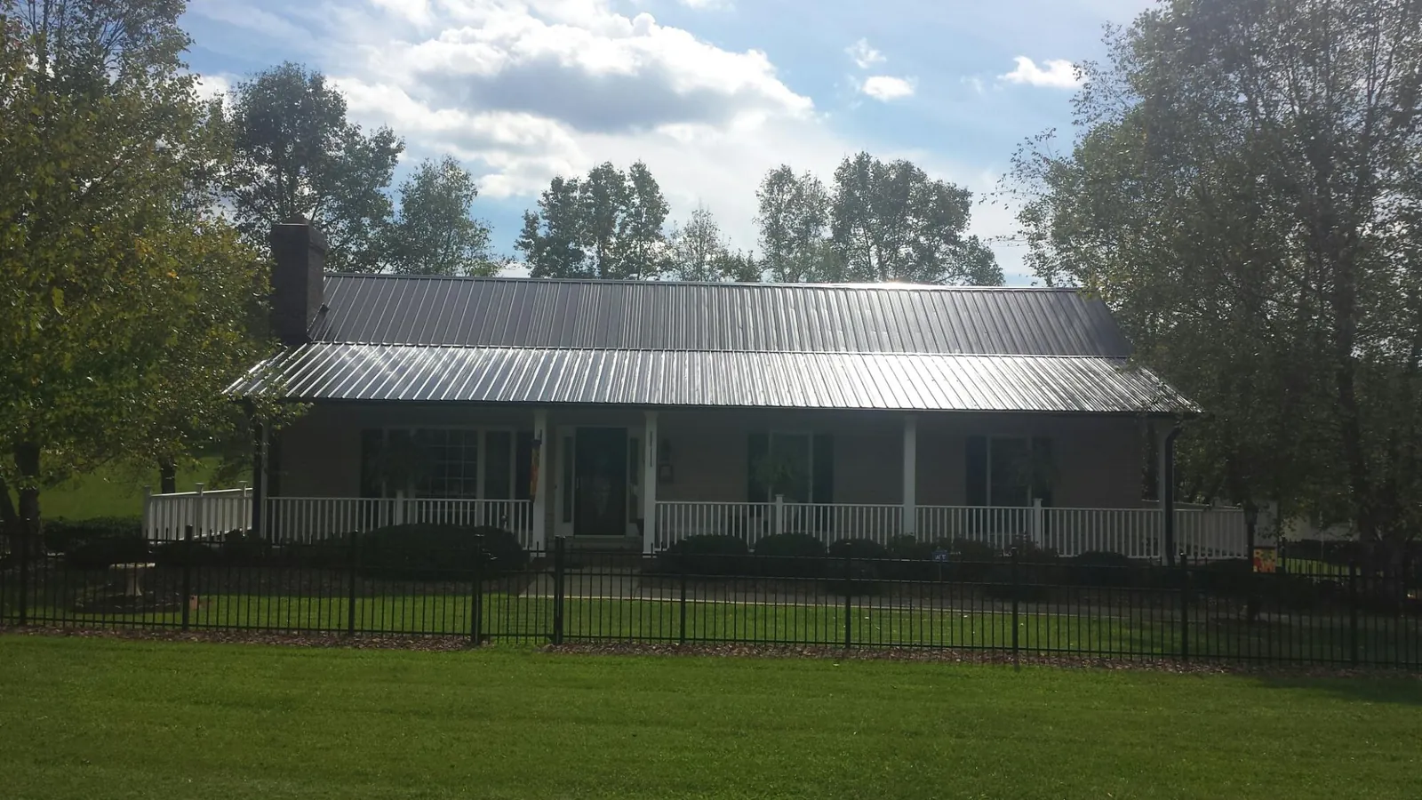 Gray metal roof on a brick ranch with a full width front porch — Gutter Guard Installation work by our crew in Fountainville