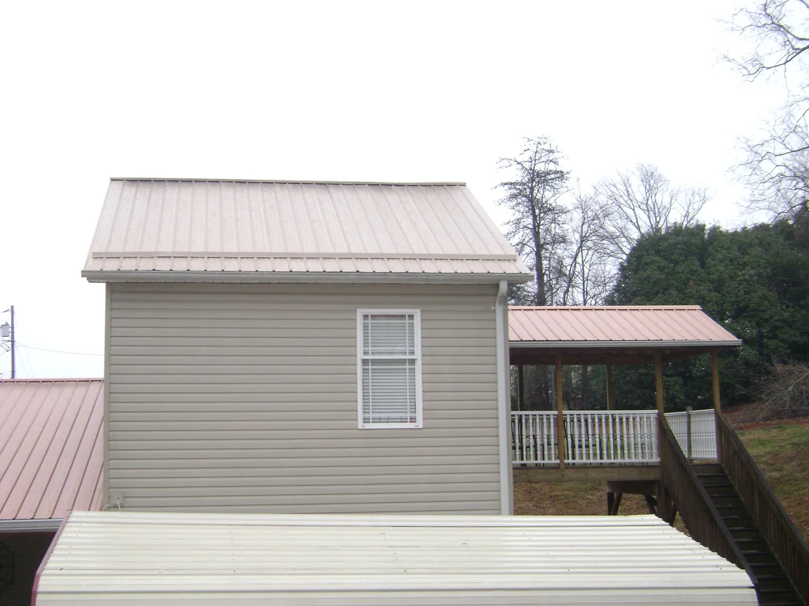 Tan metal roofs on a two story addition and attached porch, from a Roof Replacement job in Fountainville