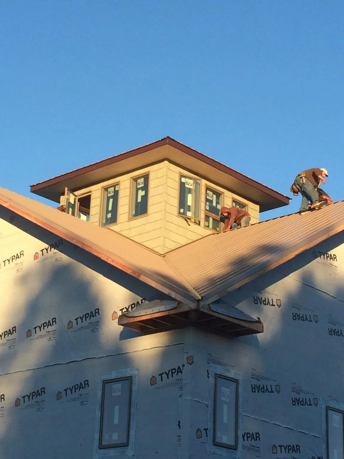 Roofers working around a rooftop cupola on a new metal roof at sunset — Roof Waterproofing in Fountainville by Roofing Brothers
